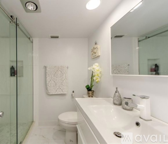 A white bathroom with a toilet, sink, and a glass shower stall.