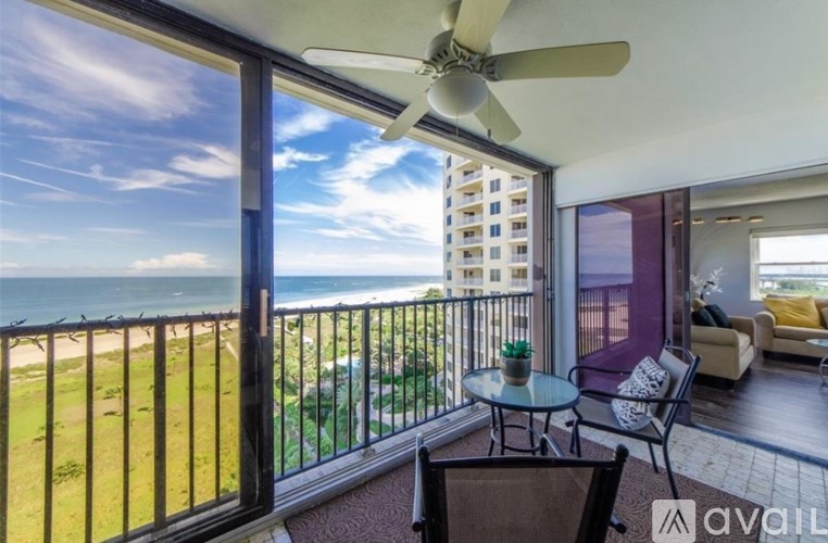 A balcony with a table and chairs overlooking the beach.