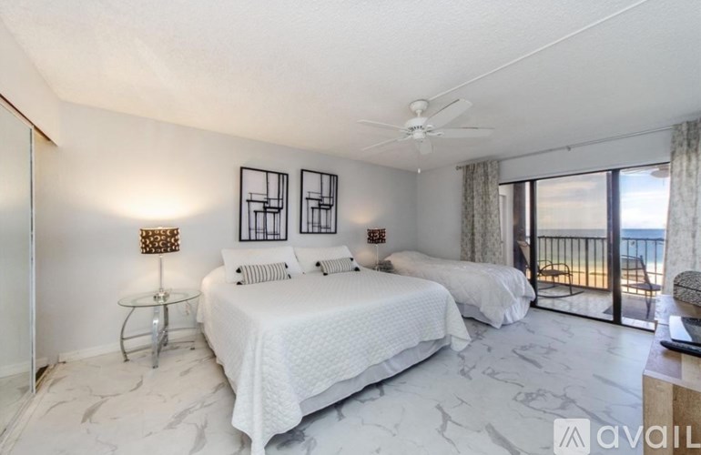A bedroom with two beds and a balcony overlooking the ocean.