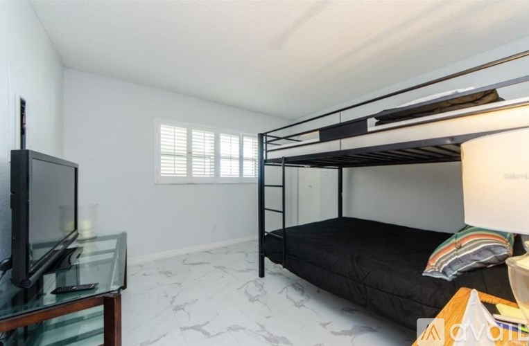 A room with a bunk bed, a television, and a glass table.