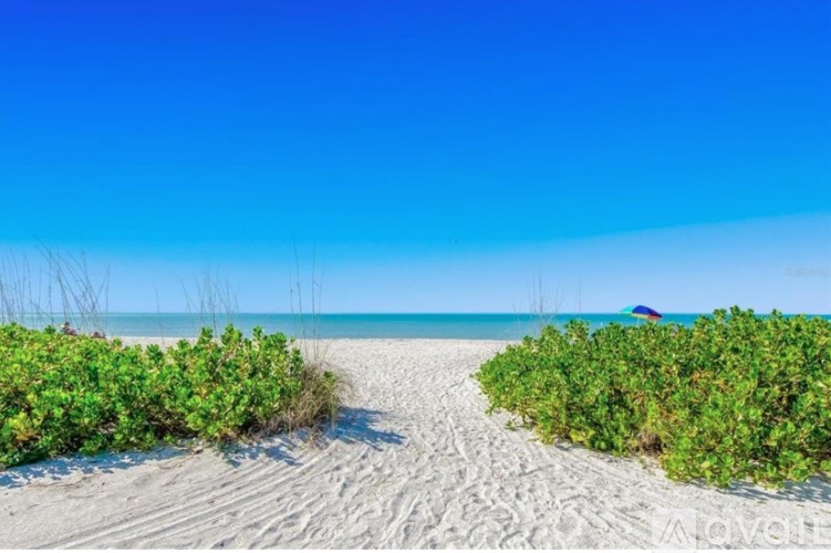 A beach scene with a clear blue sky and a boat in the distance.