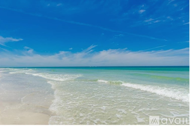 A beach with waves coming in from the sea under a clear blue sky.