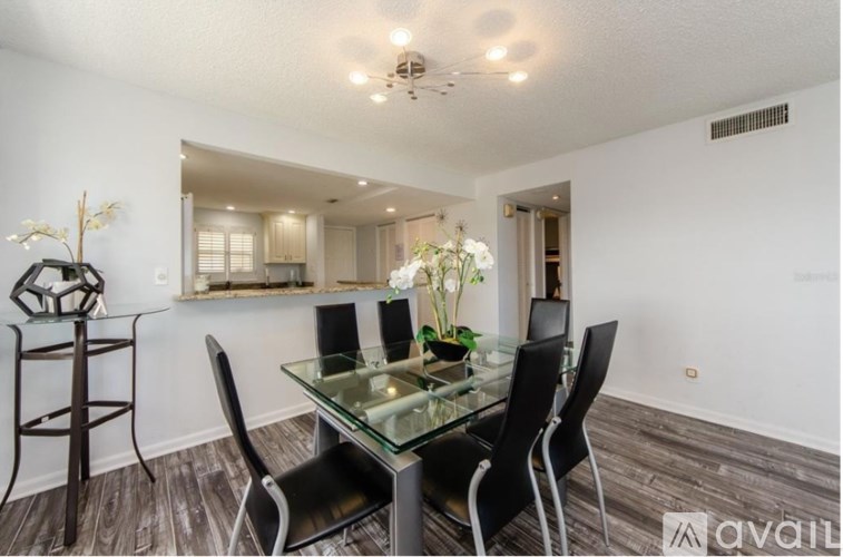 A glass dining table with four chairs in a room.