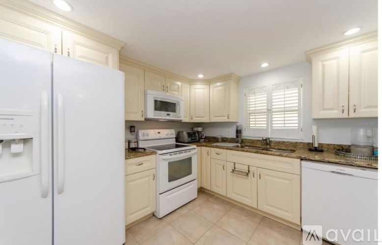 A kitchen with white appliances and cabinets.
