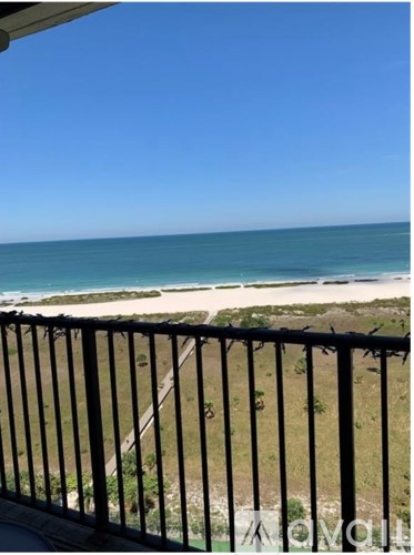 A balcony overlooks a beach with a clear blue sky.
