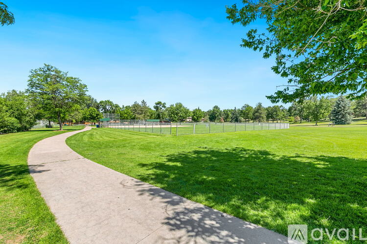 A pathway in a park with a fence and trees.