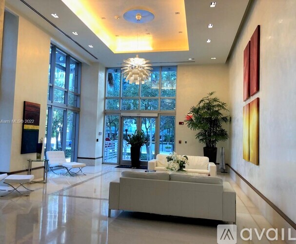 A spacious lobby with a white sofa, a potted plant, and a chandelier.