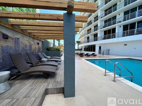 A wooden deck with lounge chairs and a pool next to a tall building.