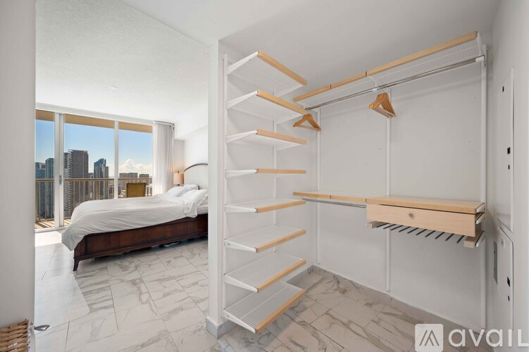A bedroom with a large bed and a window overlooking a cityscape.