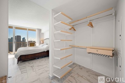 A bedroom with a large bed and a window overlooking a cityscape.