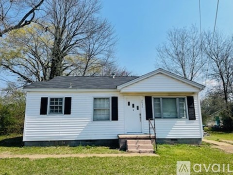 A small white house with a black roof and a porch.