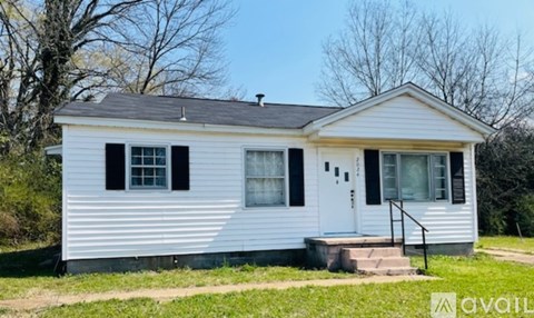 A white house with a black door and windows is for sale.