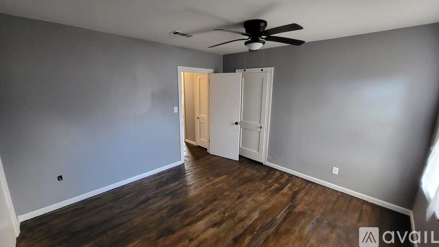 A room with a ceiling fan and wooden flooring.