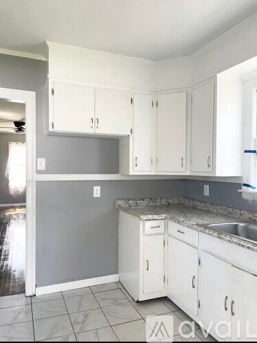 A kitchen with white cabinets and a grey backsplash.