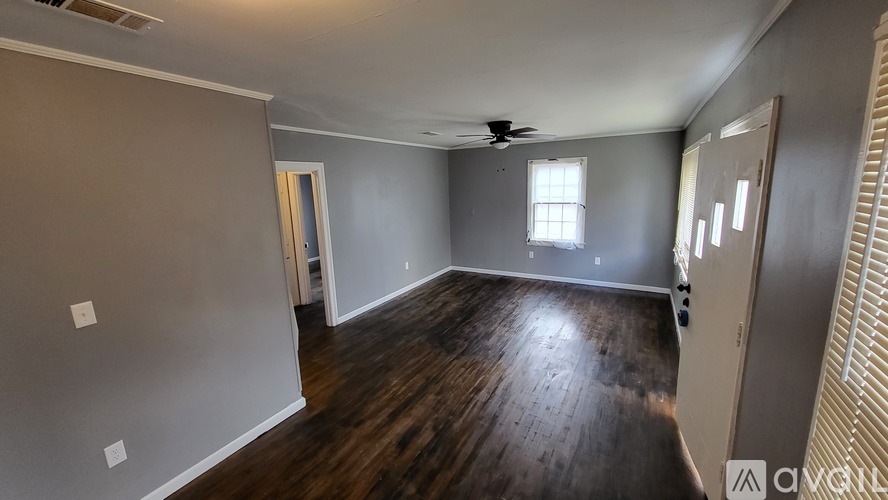 A spacious room with wooden floors and a ceiling fan.