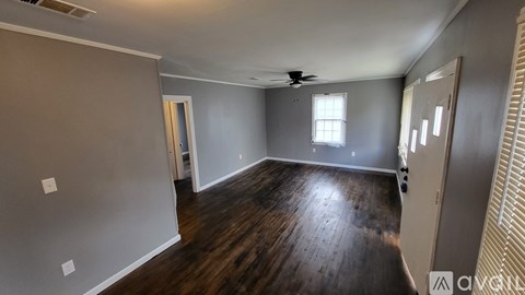 A spacious room with wooden floors and a ceiling fan.