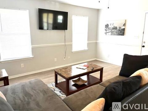 A living room with a couch, coffee table, and a painting on the wall.