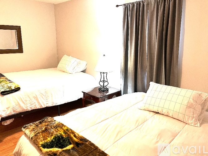 A bedroom with two beds and a nightstand with a lamp.