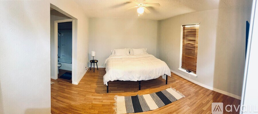 A bedroom with a bed, nightstand, and window with blinds.