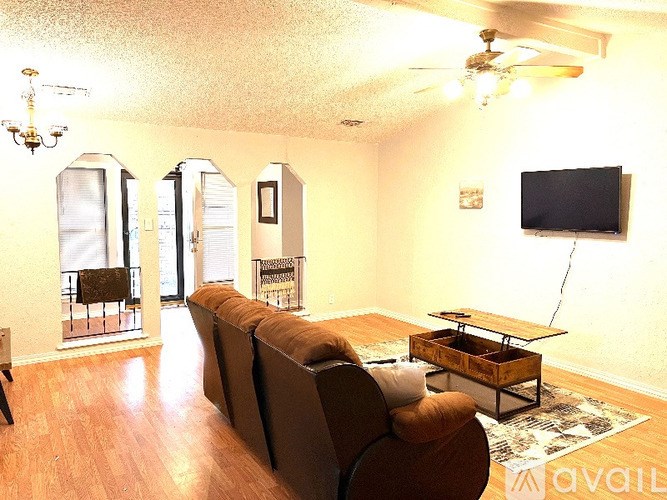 A living room with a brown couch and a flat screen TV mounted on the wall.