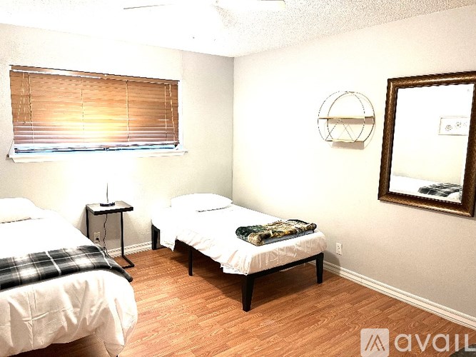 A bedroom with two beds and a window with blinds.