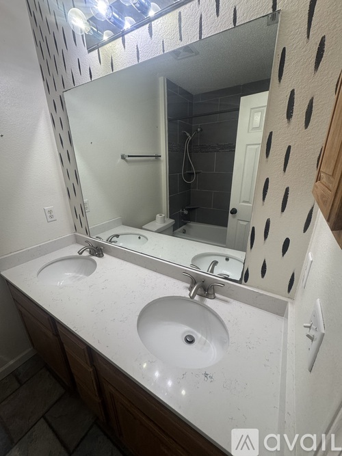 A bathroom with a white counter top and a mirror with a black frame.