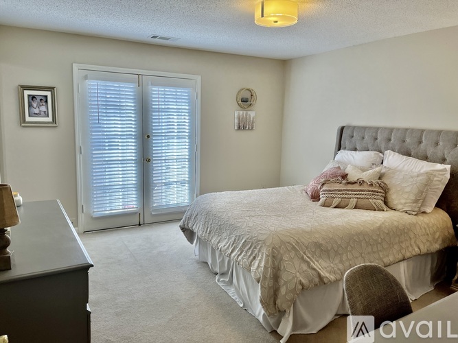 A bedroom with a bed, dresser, and window with blinds.