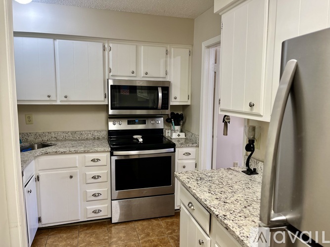 A kitchen with white cabinets and granite countertops.