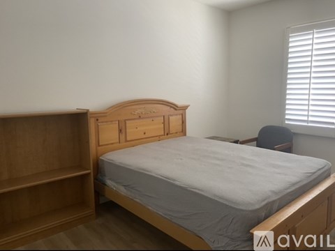 A bedroom with a bed, wooden headboard, and a chair.
