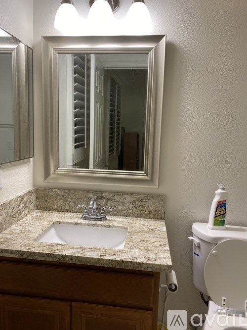 A bathroom with a marble countertop and a mirror above the sink.