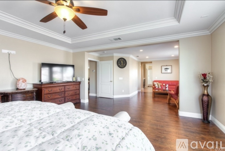 A bedroom with a large bed and a ceiling fan.