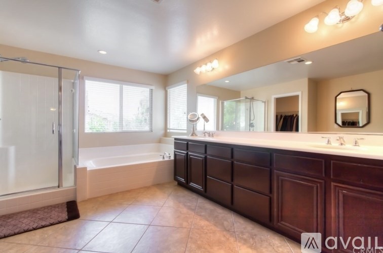 A bathroom with a large mirror, double sinks, and a walk-in shower.