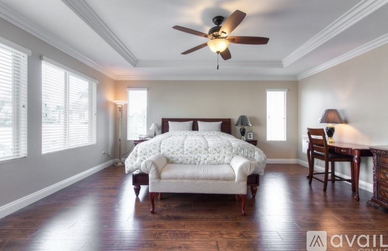 A bedroom with a bed, chair, and a ceiling fan.