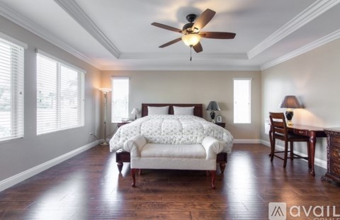 A bedroom with a bed, chair, and a ceiling fan.