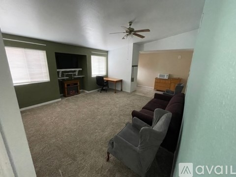 A living room with a grey couch and a ceiling fan.