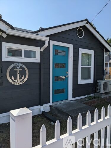 A small house with a blue door and a white fence.
