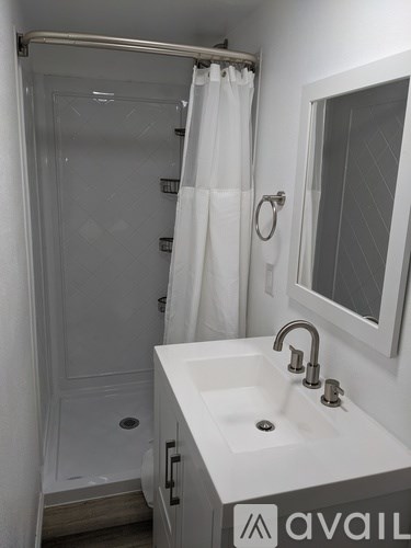 A white bathroom with a sink, mirror, and shower.