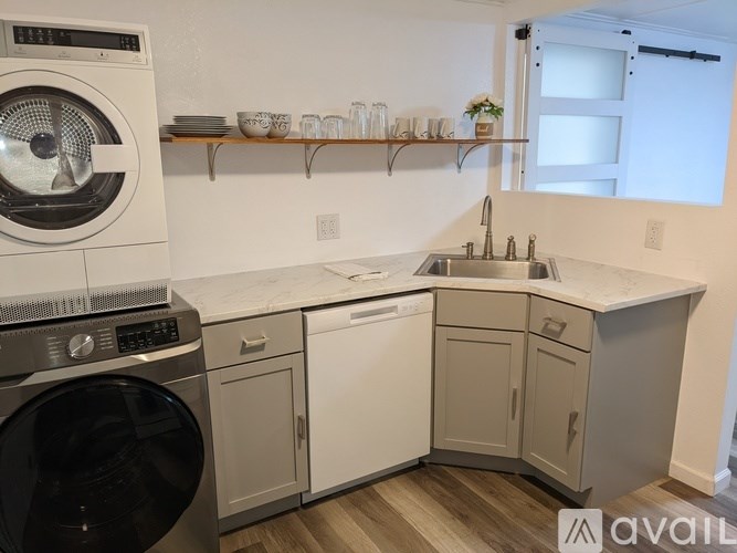 A modern laundry room with a washer and dryer, a sink, and a countertop.