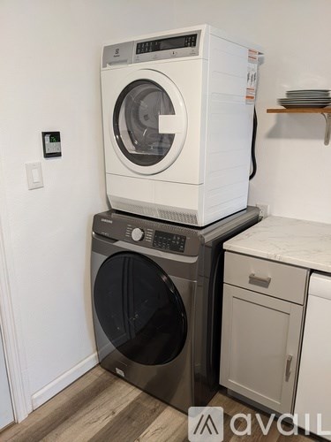 A white washing machine is stacked on top of a black washing machine.
