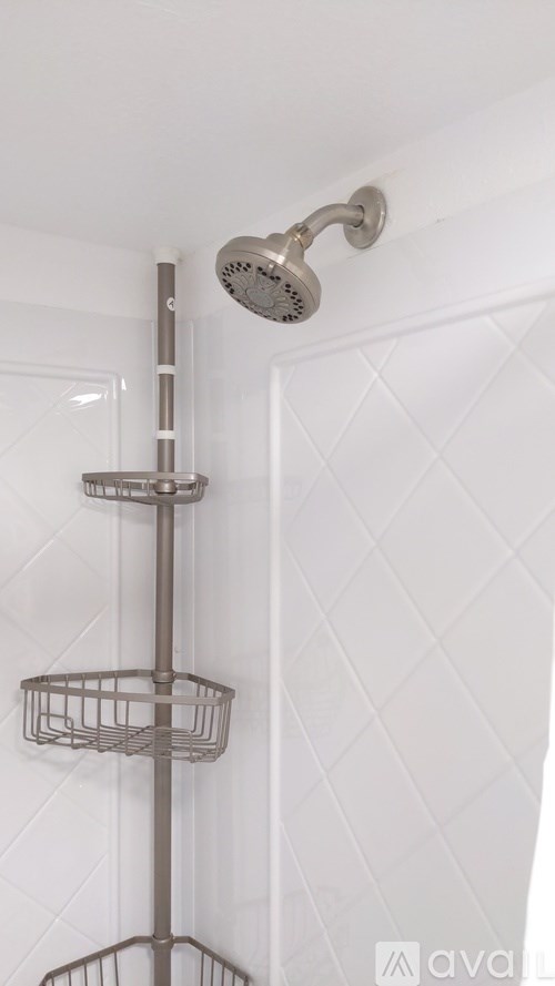 A shower head mounted on a wall with a basket hanging below it.