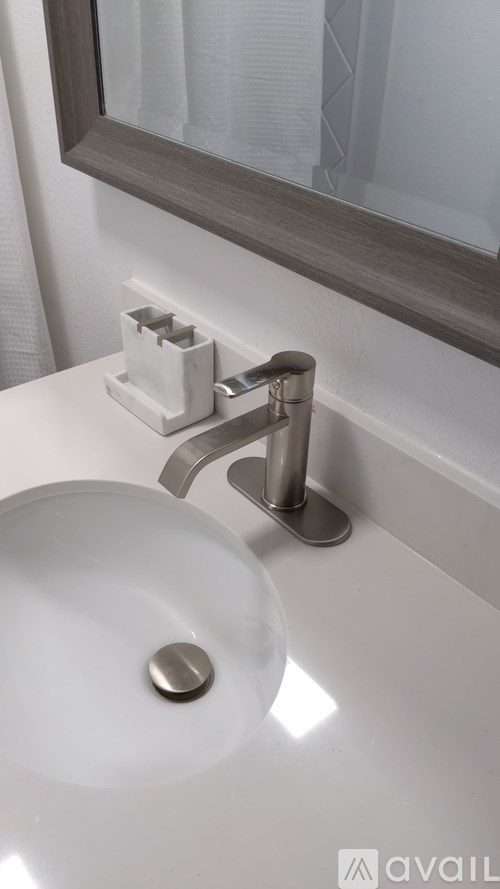A white sink with a chrome faucet and a mirror above it.