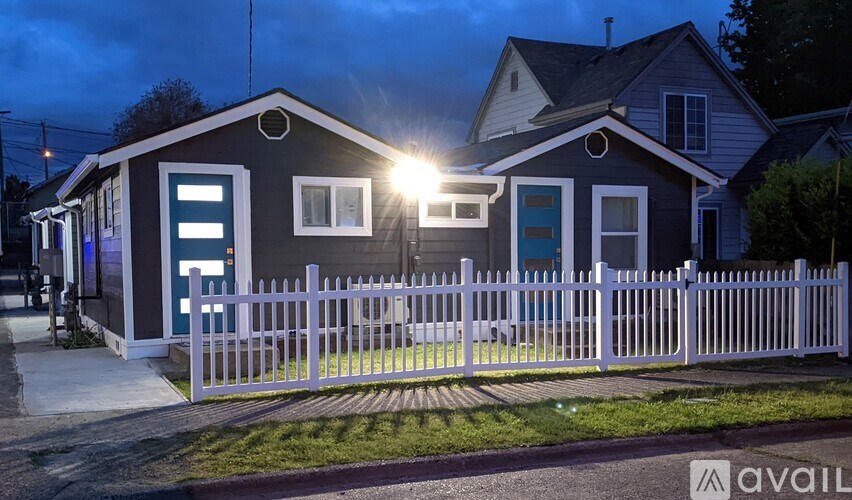 A house with a white picket fence is illuminated by a bright light.