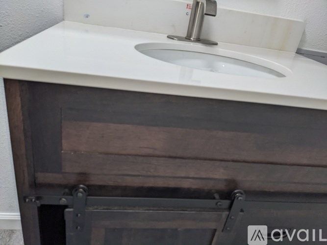 A white sink is on a counter with a wooden section underneath.
