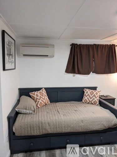 A bed with a dark headboard and a beige comforter with two pillows on it.