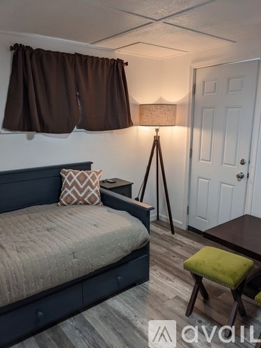 A bedroom with a bed, a small table, and a lamp.