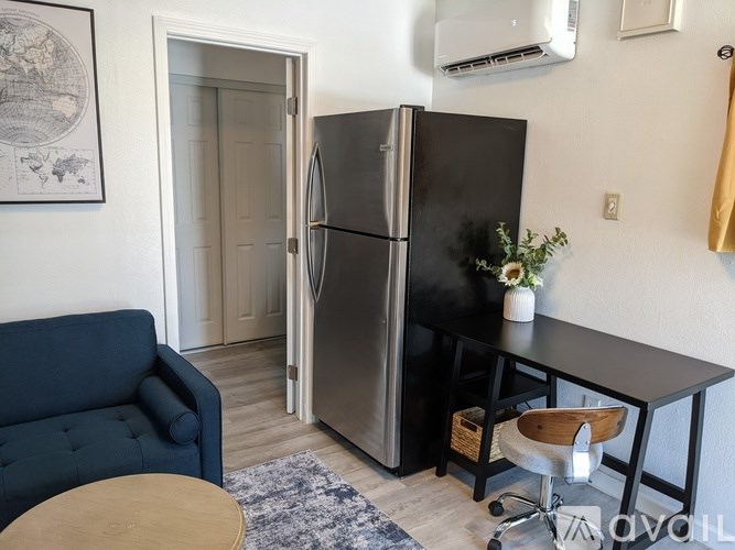 A black fridge in a room with a blue sofa and a wooden table.