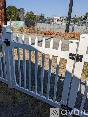 A white picket fence with a gate in front of a brown pole.