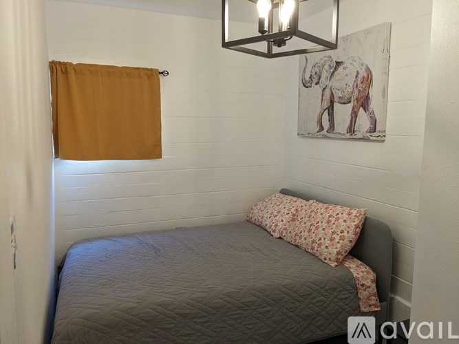 A bedroom with a bed, pillow, and a picture of an elephant on the wall.