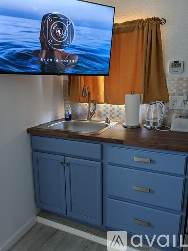 A kitchen with blue cabinets and a television displaying a camera.