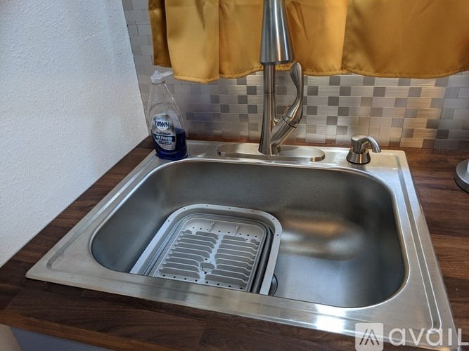 A stainless steel kitchen sink with a dish drainer underneath it.